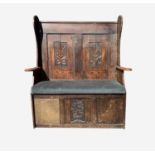 An oak and elm settle, 19th century, the back with two rectangular carved panels above a padded