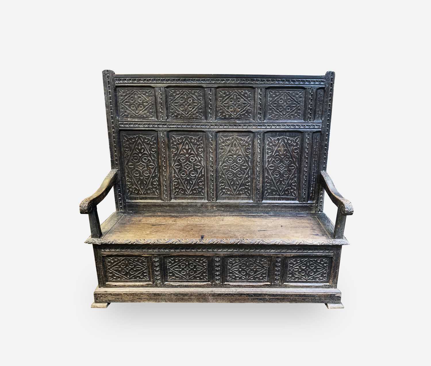 A George III oak box settle, the panel back with lozenge carved decoration, acanthus carved and