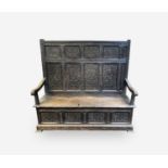 A George III oak box settle, the panel back with lozenge carved decoration, acanthus carved and