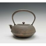 A Japanese iron teapot, 19th century, character marks by spout, height 19.5cm, width 20.5cm..