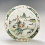 A Chinese famille verte porcelain dish, painted with a coastal scene and distant mountains, diameter