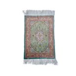 A Turkish silk rug, the pale blue field with an oval ivory medallion with scrolling flowering