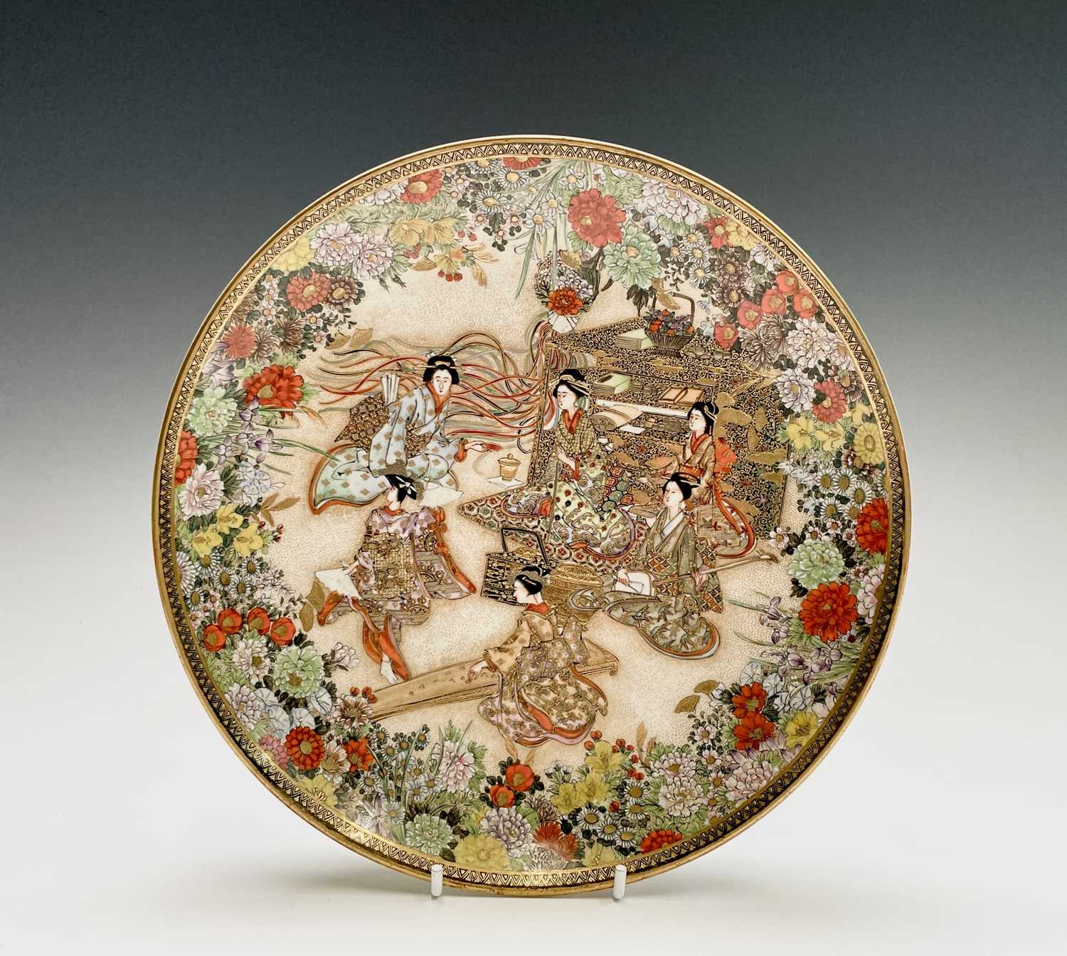 A Japanese Satsuma plate by Ryuzan, Meiji Period, gilt decorated with geisha in a garden setting,