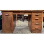 A teak pedestal desk, fitted with an arrangement of six drawers and a cupboard. Height 75cm, width