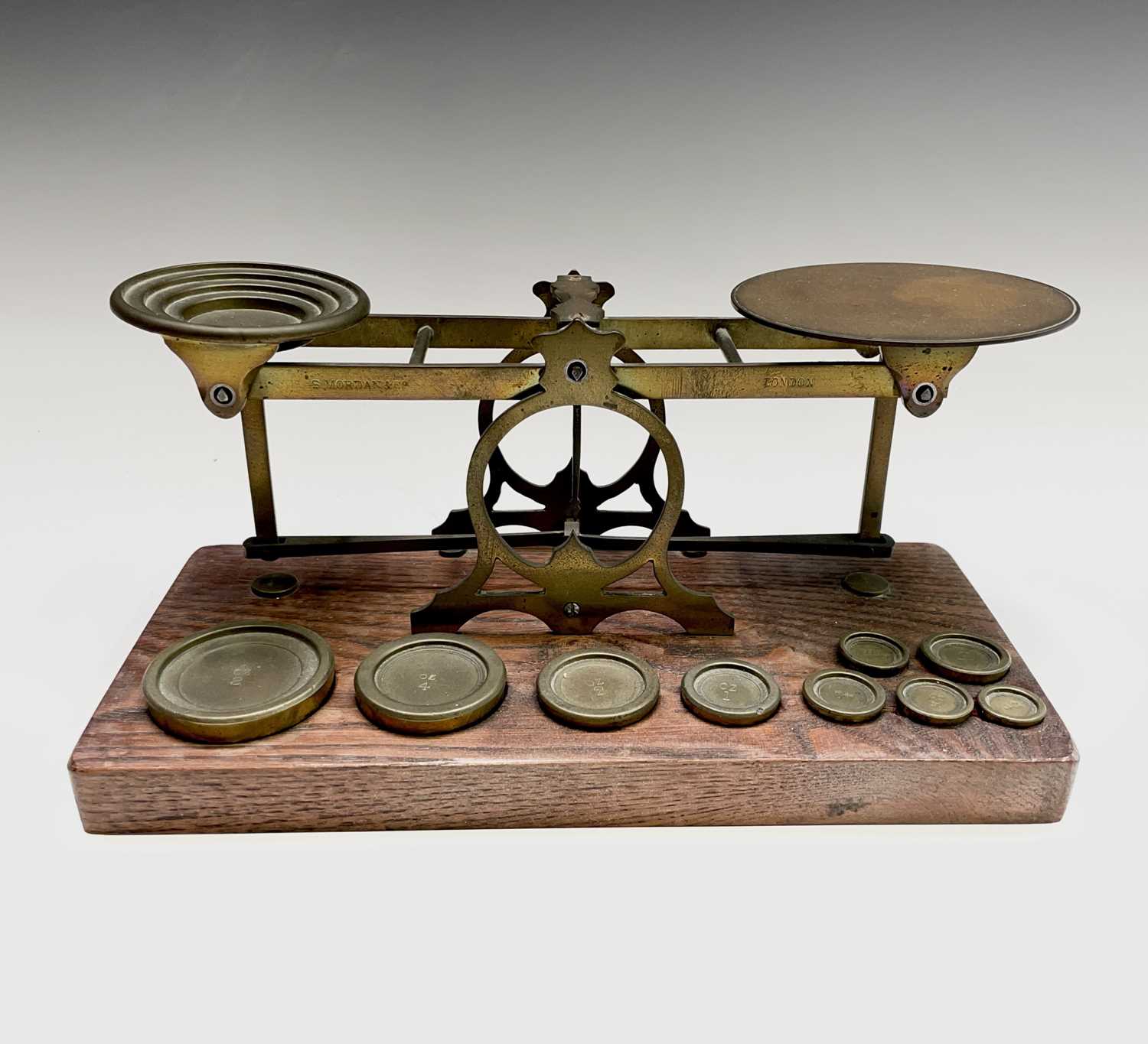 A set of late Victorian Sampson Mordan & Co brass and oak postal scales, the base set with nine