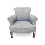 A late Victorian low armchair, raised on turned front legs and castors, height 72cm, width 73cm,