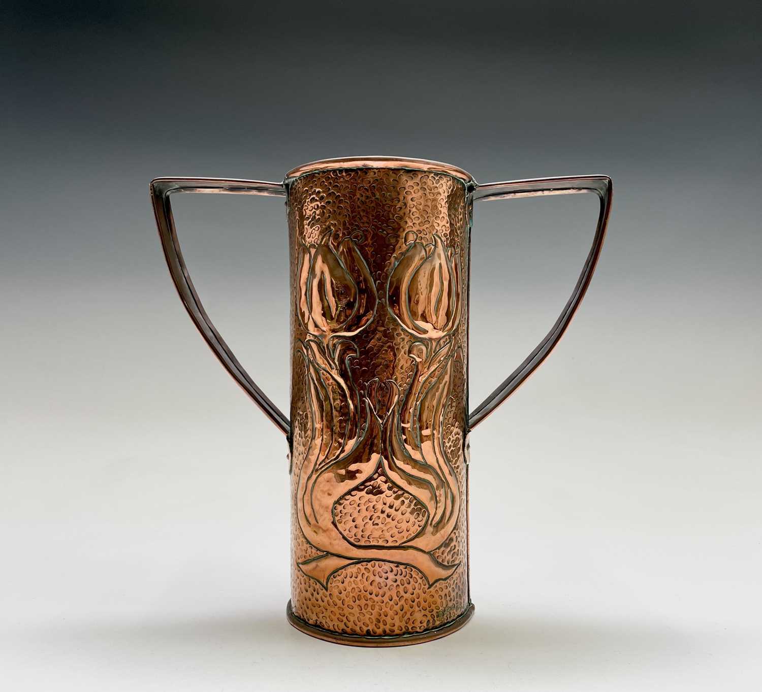 An Arts & Crafts period copper twin handled vase, the cylindrical body repousse decorated with