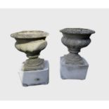 A pair of composition garden urns on associated cast concrete stands. Overall height 63cm.