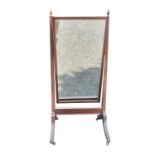 A Regency mahogany and boxwood strung cheval mirror, with brass urn finials and raised on brass