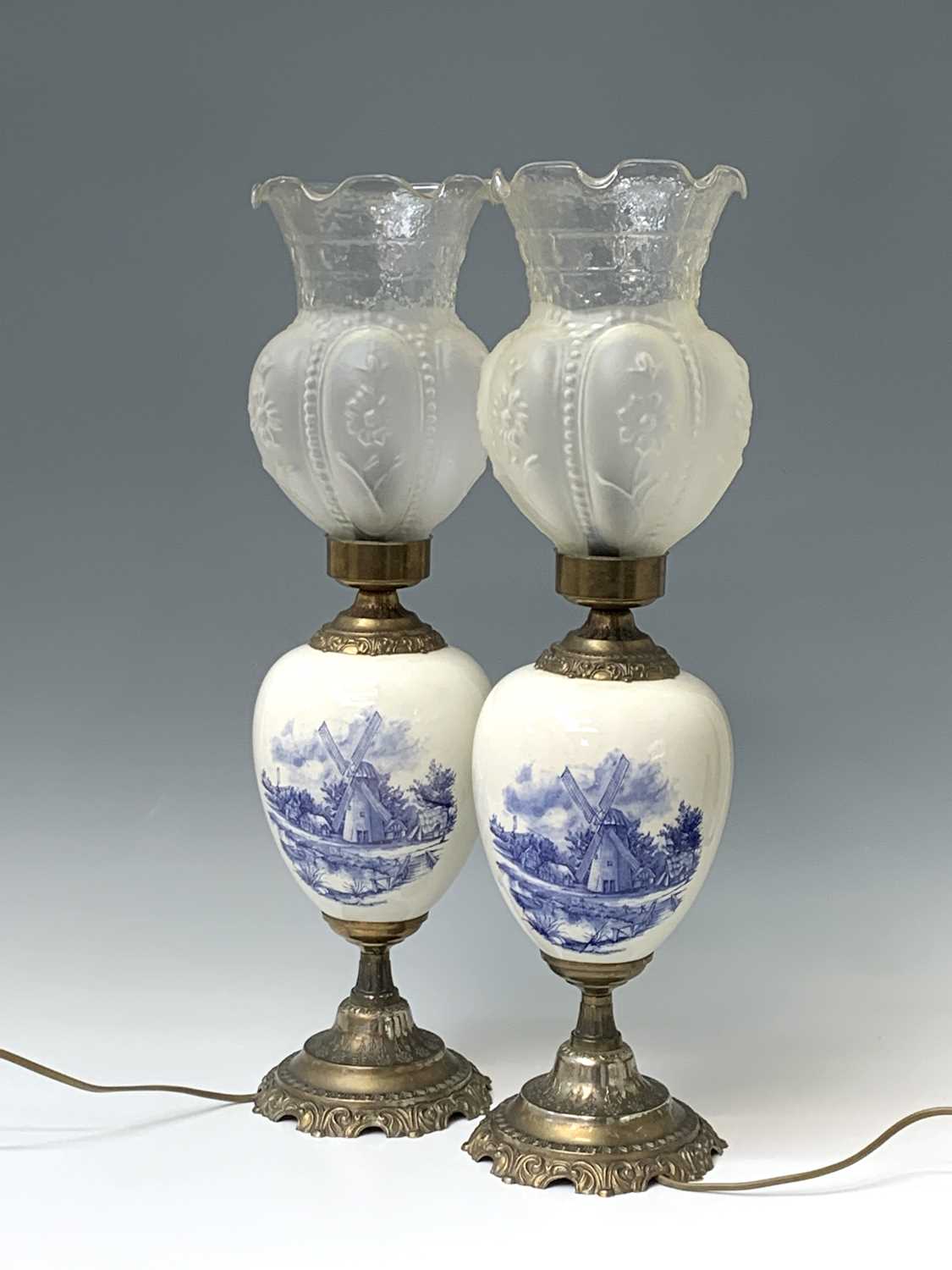 A pair of 20th century gilt metal mounted Delft table lamps with glass shades. Height 60.5cm.