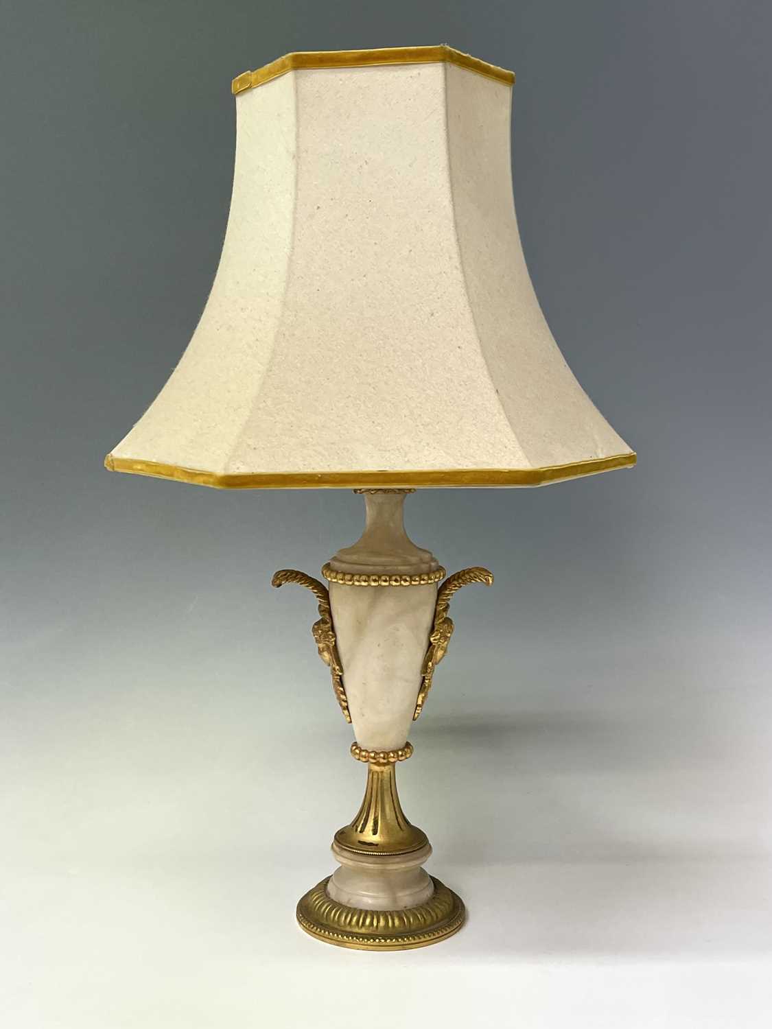 An ornate alabaster table lamp, early 20th century, with gilt metal mask handles and mounts,