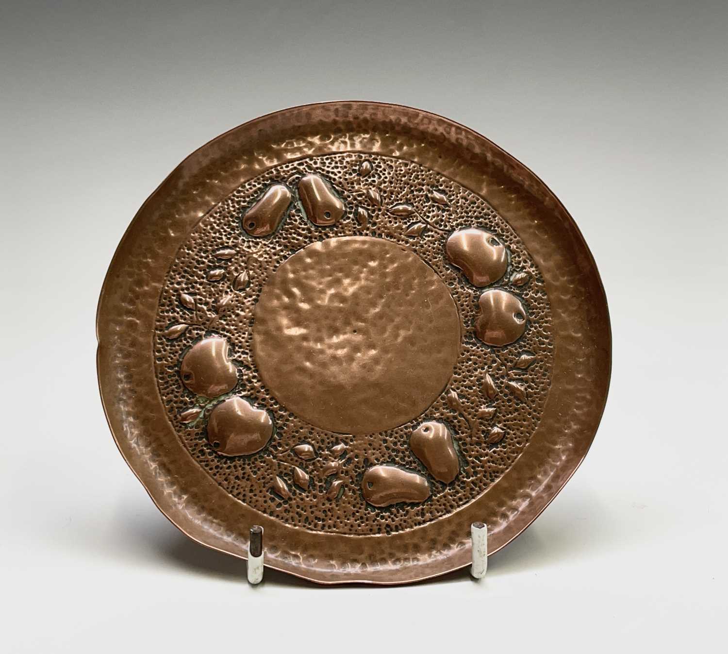 A Newlyn copper small circular dish, repousse decorated with apples and pears on a planished ground,