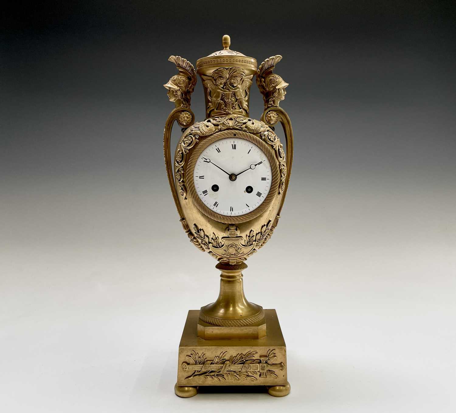 A French Empire ormolu cased mantel clock, of urn form, the covered rim applied with two winged