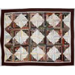 A fine patchwork quilt of rectagular, multicoloured and patterned strips with a brown and cream