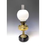 A Victorian 'Invicta' brass oil lamp, raised on circular glazed black ceramic base, with white