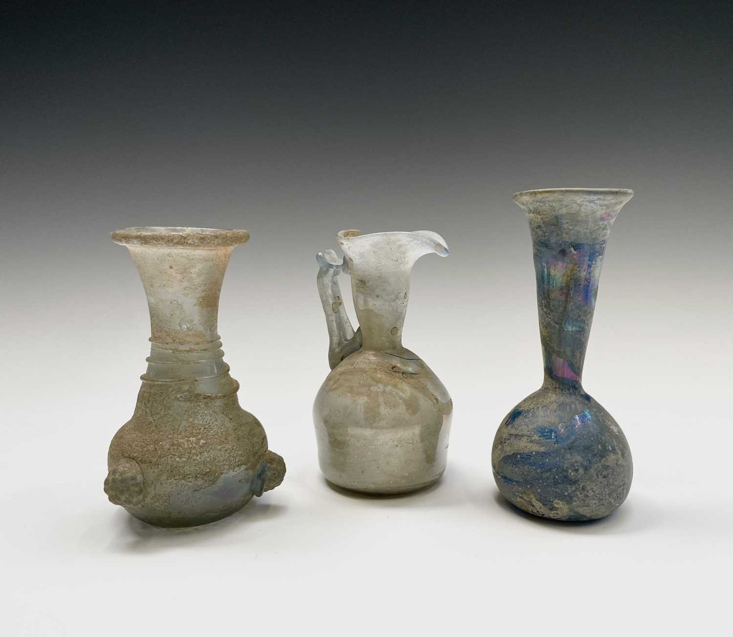 Three iridescent glass vessels, possibly Roman, comprising a ewer, height 13cm, and two vases.