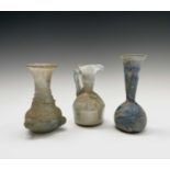 Three iridescent glass vessels, possibly Roman, comprising a ewer, height 13cm, and two vases.