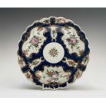 A Worcester porcelain plate, circa 1770, the blue scale ground decorated with gilt edged floral