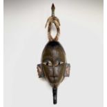 An African carved tribal mask, the horned figure with painted decoration surmounted by a bird,