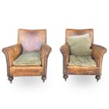 A pair of leather-upholstered club-type armchairs with studded decoration and raised on turned front