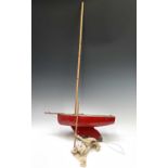 A vintage red painted pond yacht of primitive form, with weighted keel. Overall length 52cm.
