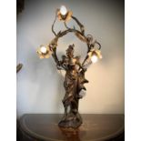 A French Art Nouveau gilt spelter table lamp, modelled as a lady standing on a foliate base, the