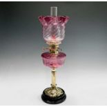 A Victorian cranberry glass and brass oil lamp, with spiral fluted shade and column support, overall