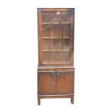 A 1930's oak bookcase/display cabinet, enclosing adjustable shelves, with two cupboard doors