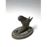 A bronze horse's mask within a horseshoe raised on wood grain effect oval wall mount. Height 21cm,