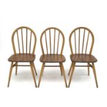 A set of three Ercol beech and light elm hoop back dining chairs, stamped to the underside with