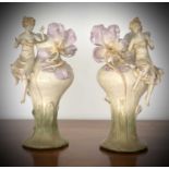 A pair of Austrian Art Nouveau porcelain figural vases, moulded with seated females beside lilies