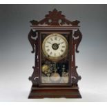 An American mantel alarm clock, by Seth Thomas, late 19th century, the walnut case with carved sides