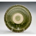 A Chinese celadon dish, Ming Dynasty, with a part glazed central roundel, within a raised