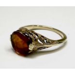 An American gold ring set an orange brown stone in a pierced and engraved shank Size M