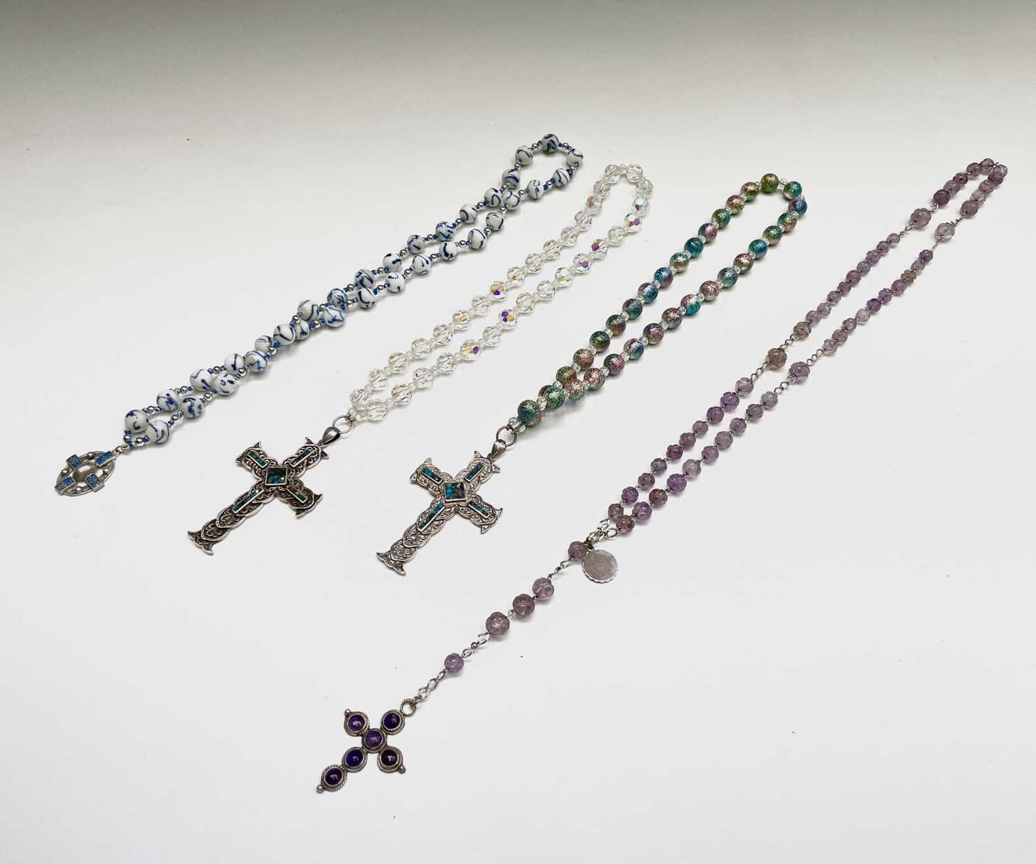 A rosary with carved amethyst beads and amethyst set silver cross, two chased silver crosses each