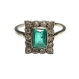 An 18ct gold and platinum, diamond and emerald ring. The emerald, rectangular cut and calculated