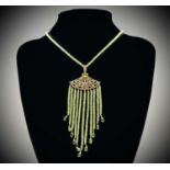 An Egyptian revival silver-gilt pendant with peridot beaded graduated tassels ending with