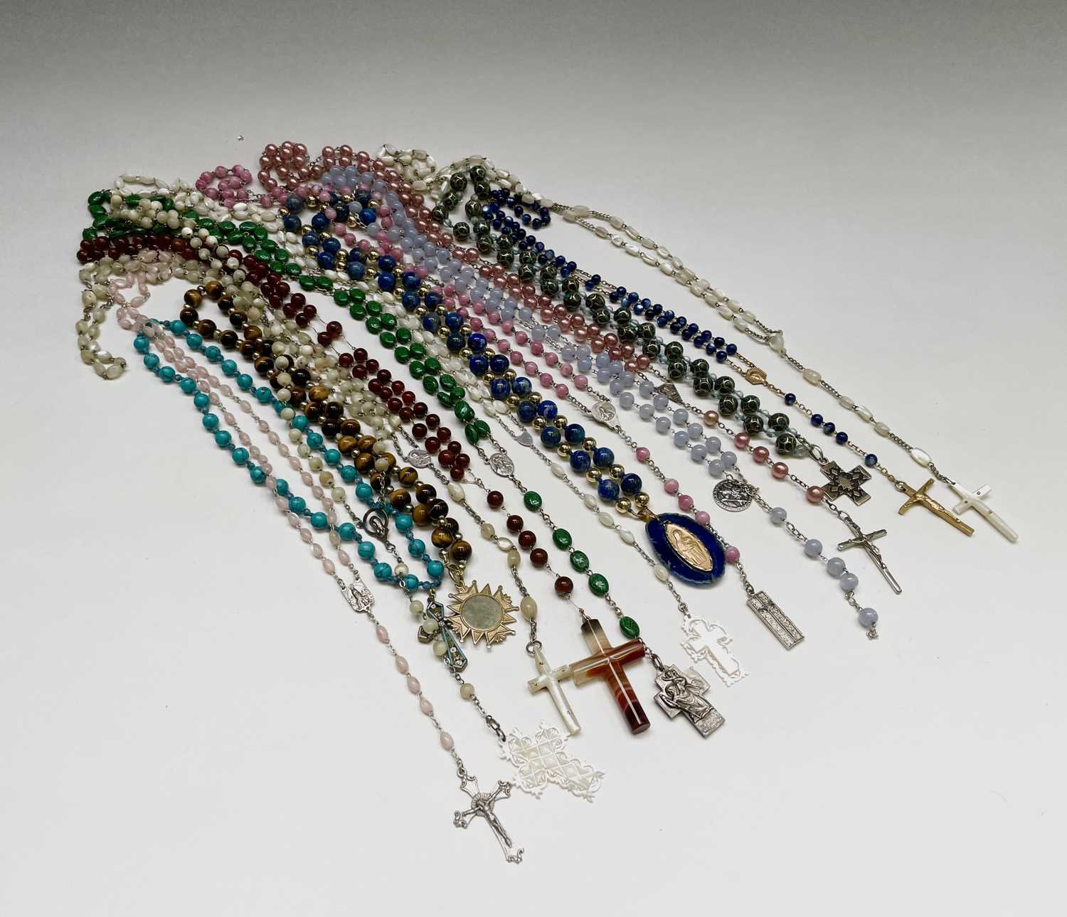 Fifteen rosary bead necklaces, all with unique decorative crosses.