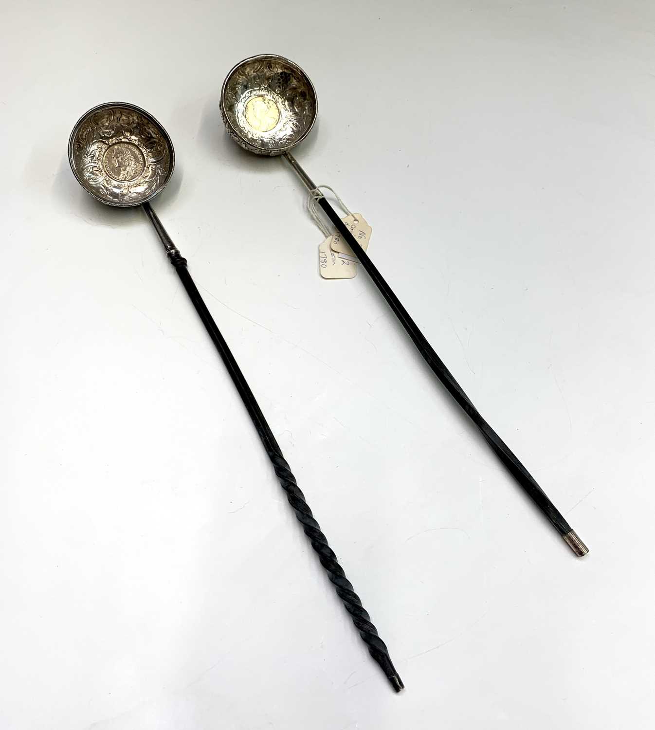 Two silver punch ladles with whale bone handles, both of round form, coin set with ornate chasing.