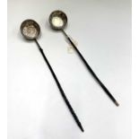 Two silver punch ladles with whale bone handles, both of round form, coin set with ornate chasing.