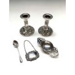 A pair of low embossed filled silver candlesticks, a silver tea strainer, a silver port label and