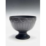 A Wedgwood black basalt pedestal bowl, 20th century, the exterior moulded with swags and vertical