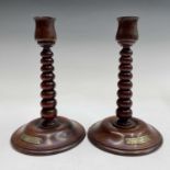 A pair of 20th century turned teak candlesticks, each bearing a brass plaque inscribed 'MADE FROM