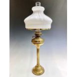 A brass oil lamp, circa 1900, with fluted opaque glass shade on a fluted column support. Height