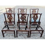 A set of three George III mahogany dining chairs, the splats with interlaced scrolls, raised on
