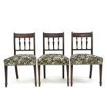 A set of three Regency mahogany dining chairs with turned and carved spindle backs, on square