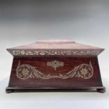 A Regency rosewood and cut brass inlaid tea caddy of sarcophagus form, the lid opening to reveal two