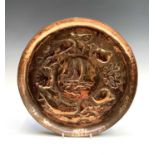 A Newlyn copper circular small charger, repousse decorated to the centre with a fishing boat