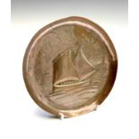 A Newlyn copper circular small pin tray, repousse decorated with a fishing boat, stamped 'NEWLYN',
