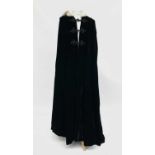 A 20th century ladies black velvet opera cape, with black cord fastenings and ermine-trimmed hood.